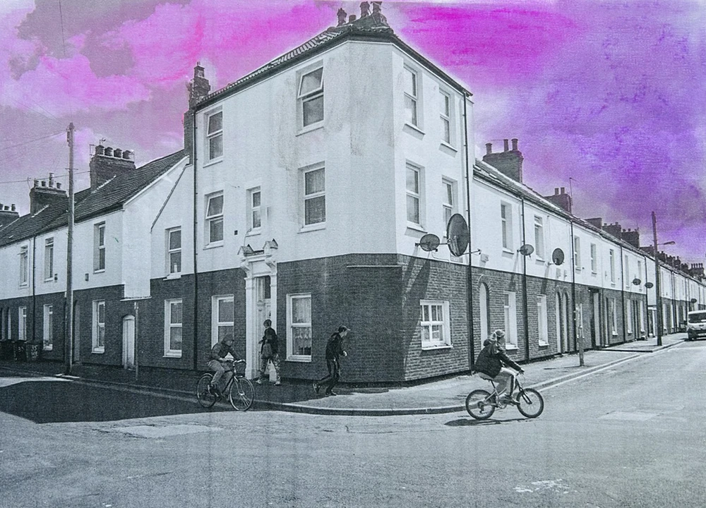Black and white street scene with white terraced houses, cyclists, and vibrant purple sky backdrop