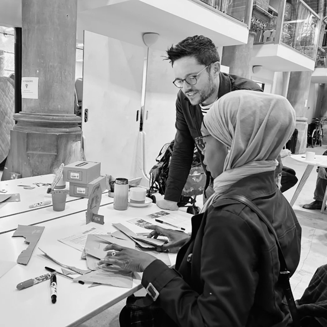 Man and woman around a desk creating artwork with cardboard
